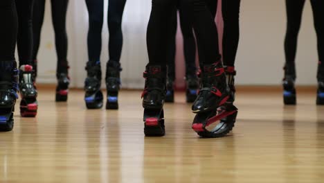 Sports-girls-are-preparing-for-a-workout-in-boots-Кangoo-jumps-in-a-large-gym