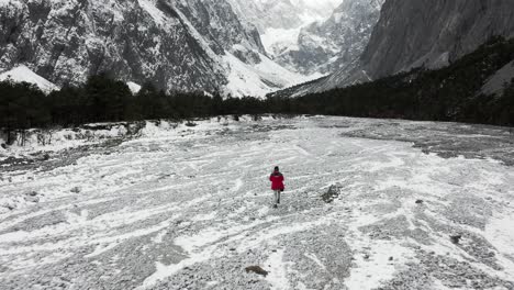 Hiker-exploring-old-glacier-river-valley-in-Yulong-Snow-Mountains,-aerial-view