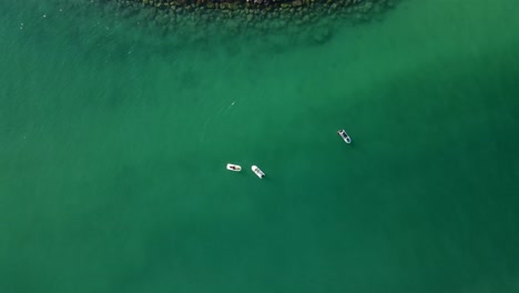 Top-view-of-jet-skis-floating-on-the-ocean,-coast-blue-green-crystal-clear-water-of-Dubai's-Mamzar-beach,-Arabian-Sea,-top-tourist-attraction,-4k-Footage