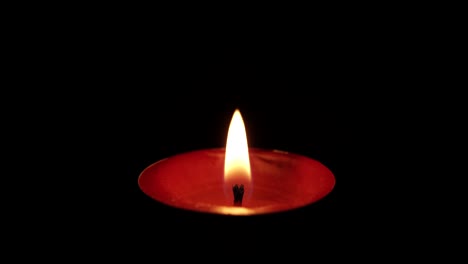 Igniting-floating-candle-flame-on-black-background,-windy-conditions-extinguishing,-macro-shot