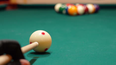 Low-Angle-Closeup-of-Cue-Ball-as-Person-Wearing-Glove-Breaks-Rack-of-8-Ball-Powerfully-on-a-Pool-Table-with-Green-Felt-and-the-Cue-Stick-Bending-as-Both-Solid-and-Stripe-Balls-Scatter,-No-Faces-in-Bar