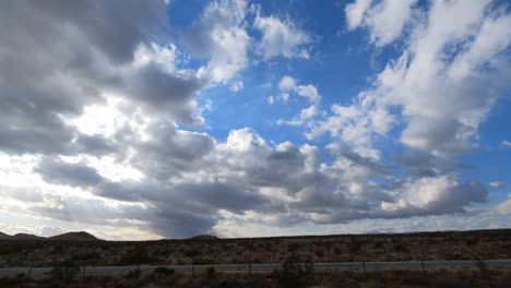 Ein-Hyperzeitrafferblick-Aus-Dem-Beifahrerseitenfenster-Eines-Autos-Auf-Die-Mojave-Wüstenlandschaft-Und-Die-Wolkenlandschaft