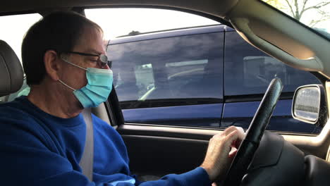 Man-With-Face-Mask-Wiping-And-Disinfecting-Steering-Wheel-In-The-Car---handheld,-close-up