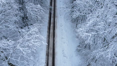 Top-Down-Aerial-Winter-View-Of-Snow-Covered-Forest-And-Road-In-The-Middle---aerial-drone-shot