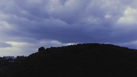 Cloudy-day-timelapse-with-hill-in-silhouette