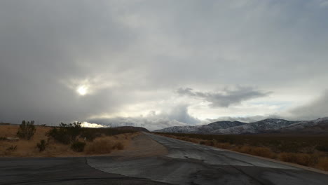 At-the-junction-of-two-roads-in-the-Mojave-Desert-wilderness,-rain-clouds-form-overhead---time-lapse