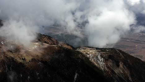 Aerial-shot-of-volcanic-rocky-mountainside-and-sulphuric-clouds