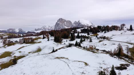 Backwards-aerial-shot-of-mountains-and-snowy-alpine-meadow-at-Seiser-Alm---Alpe-di-Siusi-plateau-in-the-Dolomites,-Italy