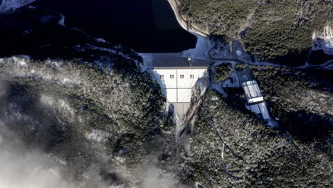 Aerial:-top-down-view-of-hydroelectric-dam-on-snowy-cold-mountainside