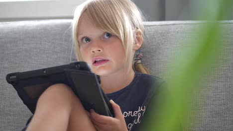 Junges-Weißes-Blondes-Hübsches-Mädchen,-Das-Innen-Mit-Tablet-computer-Spielt
