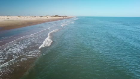Stationary-aerial-drone-view-of-vehicle-approaching-on-beach-on-a-gulf-coast-barrier-island-on-a-sunny-afternoon---South-Padre-Island,-Texas