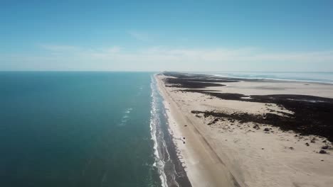 Drone-high-angle-view-of-surf,-beach-and-sand-dunes-at-low-tide-on-a-gulf-coast-barrier-island-on-a-sunny-afternoon,-luguna-on-far-side-of-island-is-visible---South-Padre-Island,-Texas