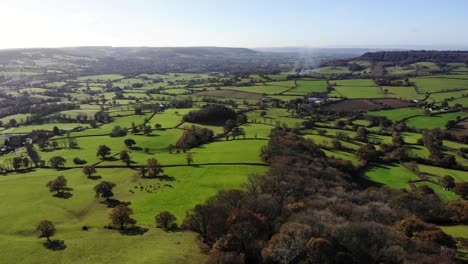 Aerial-backwards-shot-looking-over-green-fields-and-the-East-Devon-Countryside-England-UK
