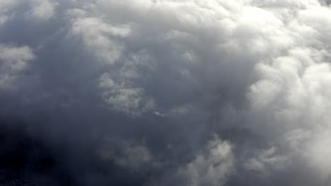 Dramatische-Dicke-Wolken-über-Berggipfeln,-Luftaufnahme-über-Wolken