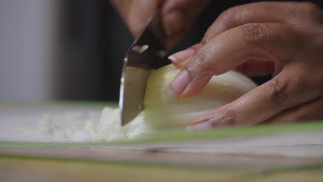 Chopping-onions-on-a-cutting-mat---isolated-close-up-with-African-American-hands