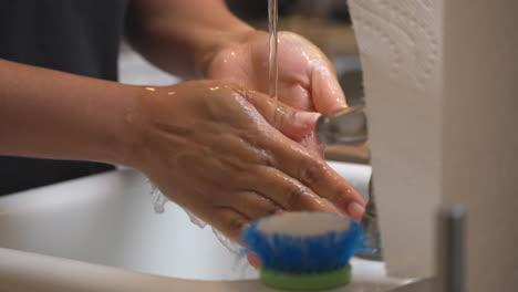 Afroamerikanerin-Spült-Seife-Von-Ihren-Händen-In-Der-Küchenspüle---Isoliert-Nah-Oben