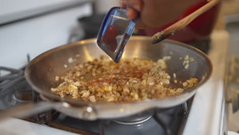 Adding-a-liquid-and-tomato-paste-to-a-pan-full-of-fried-onions-and-meat-for-a-homemade-recipe