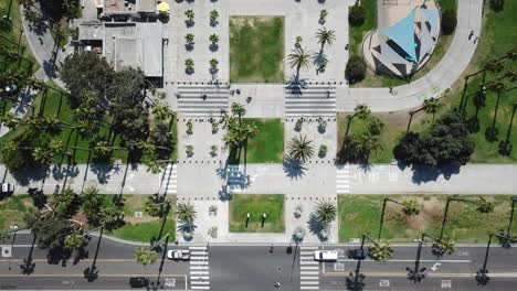 Aerial-birdseye-view-above-Los-Angeles-public-walkway-moving-forward-to-palm-tree-sandy-beachfront
