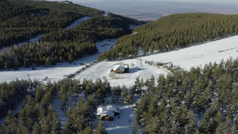 Ehrfurchtgebietender-Blick-über-Einen-Kiefernwald-Mit-Strahlend-Weißem-Schnee-Und-Einer-Verlassenen-Hütte