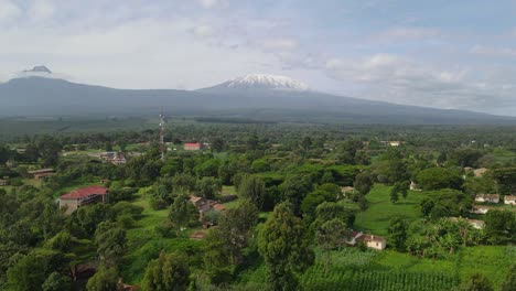 Estructuras-En-Follaje-Denso-Con-El-Monte-Kilimanjaro-Que-Se-Eleva-Detrás-Durante-La-Mañana-Brumosa-En-Kenia,-áfrica