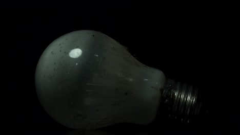Staubbedeckte-Wolfram-Glühlampe,-Die-Eine-Leuchtende-Glühbirne-Auf-Schwarzem-Hintergrund-Reflektiert