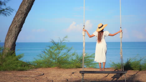Back-view-of-girl-standing-on-swing-in-front-of-sea
