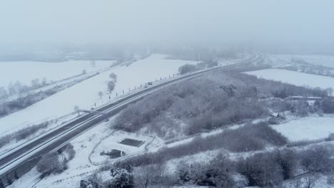 Dangerous-driving-conditions,-heavy-snow-falling-over-freeway,-aerial-drone-shot