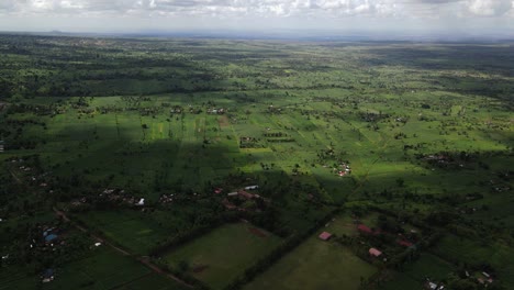 Beautiful-aerial-view-of-the-green-farming-landscape-of-Kimana,-Kenya-as-the-sun-shines-through-the-clouds-creating-a-scenic-natural-spotlight