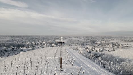 Snowy-Cross-At-Vineyard-Plantation-With-Mountains-During-Winter-In-Offenburg,-Germany