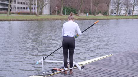 Female-rower-preparing-to-go-out-on-Utrecht-canal-for-training-in-a-single-scull-boat
