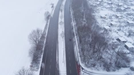 Car-driving-on-a-black-asphalt-road-cleared-from-snow-neer-Bochum-in-Germany
