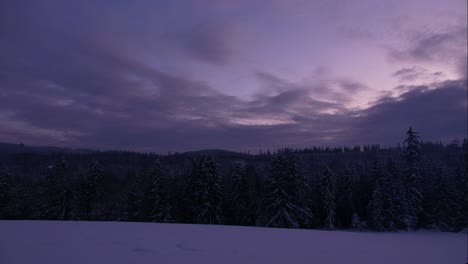 Time-lapse-of-clouds-at-sunset-in-snowy-hill-above-forest,-Poland,-wide-shot