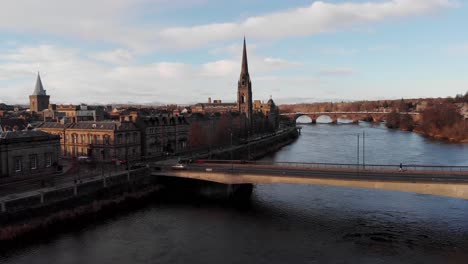Ascending-aerial-shot-showing-cars-on-bridge,lighting-buildings-and-church-during-sunny-day-in-Perth-City,Scotland