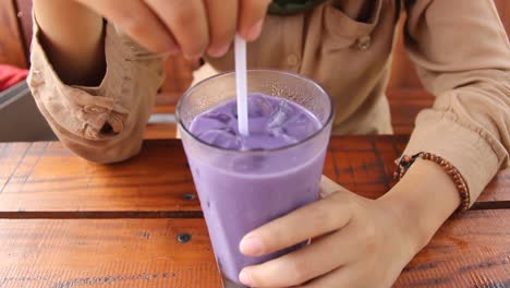 a-woman-is-enjoying-purple-ice-in-a-wooden-cafe