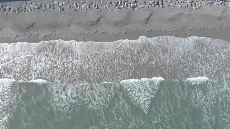 Absteigende-Vogelperspektive-Von-Meereswellen,-Die-Auf-Den-Sand-Krachen-Und-Sich-Dann-Zurückziehen