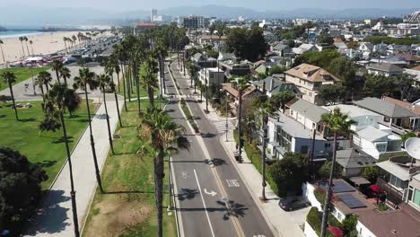 Aerial-descending-view-above-Los-Angeles-beach-suburb-skyline-down-to-waterfront-neighbourhood-street