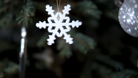 Snowflake-toy-hanging-and-waving-on-Christmas-tree-branch-close-up