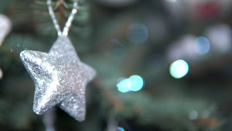 Shiny-reflective-star-shaped-toy-hanging-on-Christmas-tree,-close-up-static