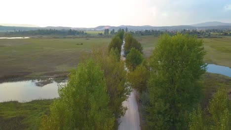 Drone-decent-shot-of-a-straight-road-in-the-countryside-across-a-river