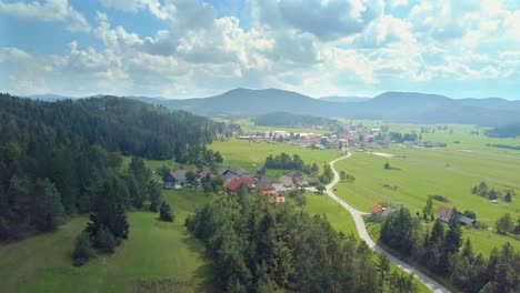 Aerial-view-of-white-clouds-above-a-town-or-village-with-the-curvy-road-at-Cerknica,-Slovenia