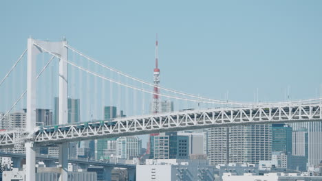Rainbow-Bridge-Over-Tokyo-Bay-With-Tokyo-Tower-And-Skyline-Against-Blue-Sky-At-Daylight-In-Tokyo,-Japan