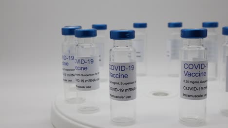 Transparent-empty-glass-vials-with-Covid-19-Vaccine-label-on-rotating-display