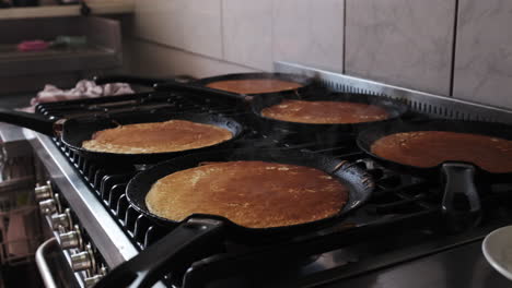 Dolly-backward-on-pankakes-being-cooked-on-the-pans-of-a-gas-oven