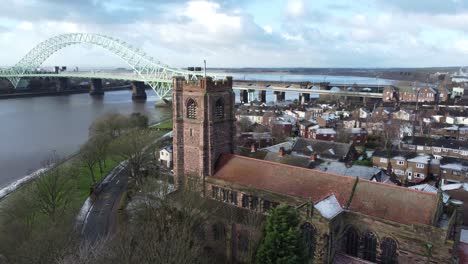 Aerial-view-industrial-small-town-frosty-church-rooftops-neighbourhood-North-West-Jubilee-bridge-England-pull-back
