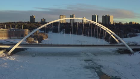 Sunset-White-Winter-Walter-Dale-Bridge-aerial-hold-facing-East-with-an-icy-snow-covered-North-Saskatchewan-River-with-hardly-any-cars-headed-one-way-North-to-the-downtown-Capital-City-of-Edmonton-1-4