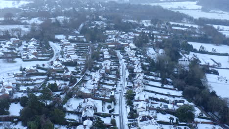 Drone-aerial-footage-of-Houses-in-England-on-a-Snowy-Morning-With-Rooftops-Covered-in-Snow-and-snow-on-the-roads,-in-English-town