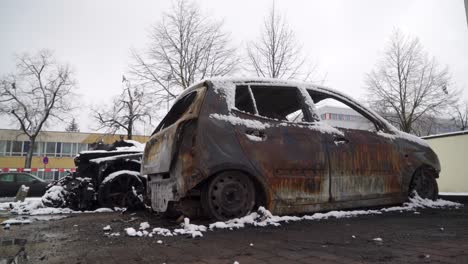 Arson-car-vandalism,-city-crime-scene-burnt-vehicle-covered-in-snow