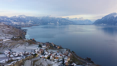 Fly-By-Rivaz-Village-In-Lavaux-Vineyard-Terraces-With-Swiss-Alps-In-Background-During-Winter-In-Vaud,-Switzerland