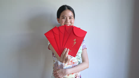 Schöne-Asiatische-Frau-Trägt-Chinesisches-Traditionelles-Kleid-Mit-Rotem-Umschlag-Oder-Rotem-Paket