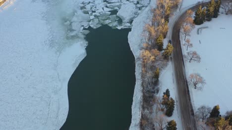 Winter-Aerial-birds-eye-view-fly-over-the-North-Saskatchewan-River-covered-with-snow-ice-and-pockets-of-cold-waters-next-to-Kinsmen-Park-of-Edmonton-Capital-City-park-on-a-sunny-afternoon-forest-3-5